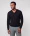 Black V-neck sweater worn with sage green trousers.