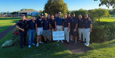 Golf outing group photo beside a sign reading "Clothing/apparel sponsor: Emma Crepeau, Jack Archer".