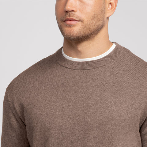 A man wearing the Anytime Crewneck Sweater Mocha Heather outdoors