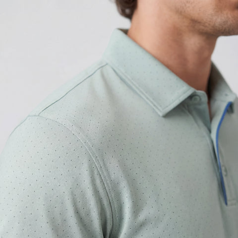 Close-up of a light gray polo shirt with a subtle pattern on a neutral background