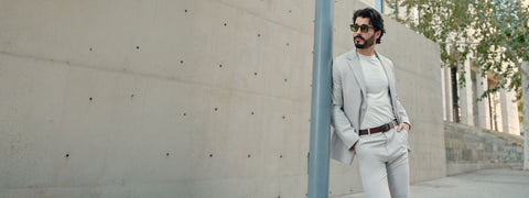 Hero banner: man in light gray suit jacket and Jetsetter Tech Pants leaning on a concrete wall in sunlight