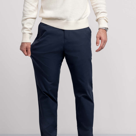 A man in the Jetsetter Tech Pant Relaxed Fit Deep Blue, sitting outdoors