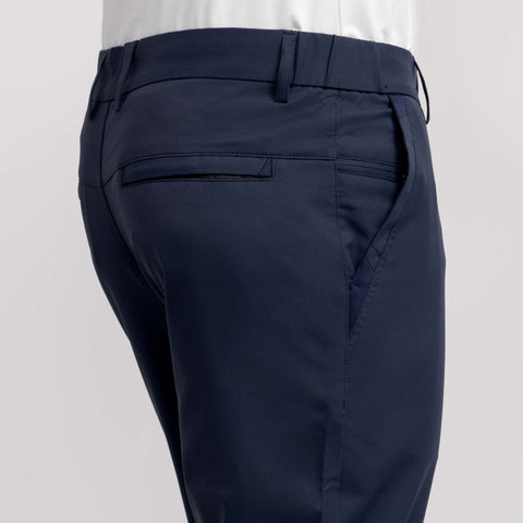 A close-up view of a person wearing the Jetsetter Tech Pant Straight Fit in navy blue with a white shirt, highlighting the side and back pockets of the wrinkle-free pants.