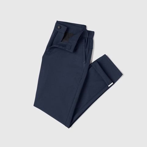A pair of Jack Archer Jetsetter Tech Pant Slim Fit in Deep Blue, neatly folded with button closure, displayed on a plain light grey background.