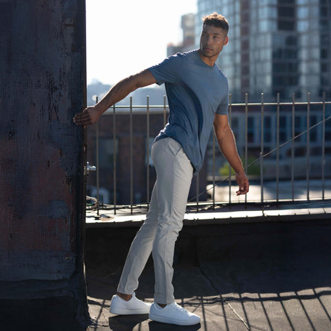 A model wearing the Jetsetter Tech Pant Classic Fit in Ice Gray, seated.