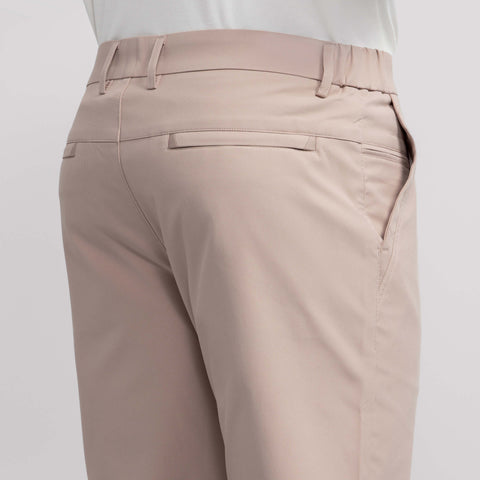 A close-up of a person wearing Jack Archer’s Jetsetter Tech Pant Slim Fit in Oak Khaki, featuring welt back pockets and belt loops, shown from the back and side with a white shirt tucked in.