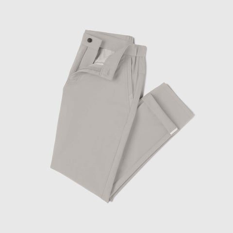 The Jack Archer Jetsetter Tech Pant Relaxed Fit in Sand Stone is shown neatly folded on a white background, featuring a light gray color, wrinkle-resistant fabric, waistband with button closure, and belt loops.