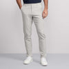 A person models the Jack Archer Jetsetter Tech Pant Straight Fit in Sand Stone, standing against a plain light gray background with hands in pockets and upper torso partially out of frame.