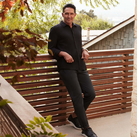 A model wearing the Jetsetter Tech Pant Slim Fit in Space Black, seated.