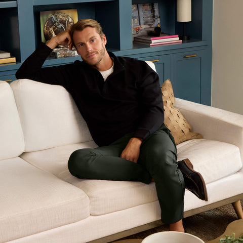 A model wearing the Jetsetter Tech Pant Straight Fit in Spruce Green, seated.