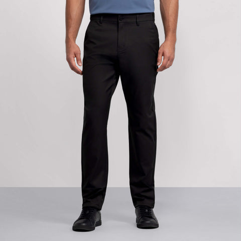 A person wearing Jack Archer Jetsetter Tech Pant Relaxed Fit in True Black stands against a plain gray background. The wrinkle-resistant pants offer a polished look. Image is cropped from the shoulders down.