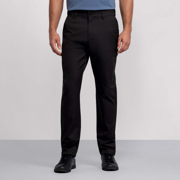 A person wearing Jack Archer Jetsetter Tech Pant Relaxed Fit in True Black stands against a plain gray background. The wrinkle-resistant pants offer a polished look. Image is cropped from the shoulders down.