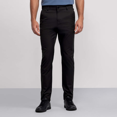 A person, shown from the waist down against a light background, wears Jack Archer’s Jetsetter Tech Pant 3-Pack in black along with black sneakers and a blue shirt.