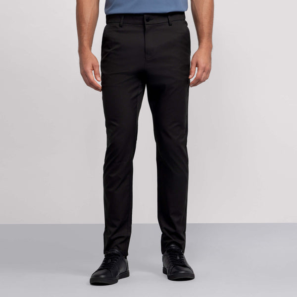 A person, shown from the waist down against a light background, wears Jack Archer’s Jetsetter Tech Pant 3-Pack in black along with black sneakers and a blue shirt.