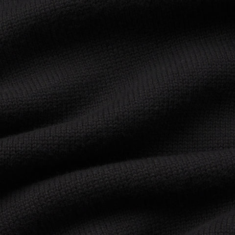 A man wearing the Jetsetter Quarter-Zip Sweater in True Black, seated outdoors.