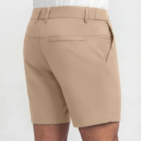 A person is shown from the back wearing Jack Archer’s Jetsetter Tech Short 7" in Sand Tan and a white shirt, highlighting rear welt pockets, belt loops, mid-length cut, wrinkle-resistant smooth fabric—ideal for travel.