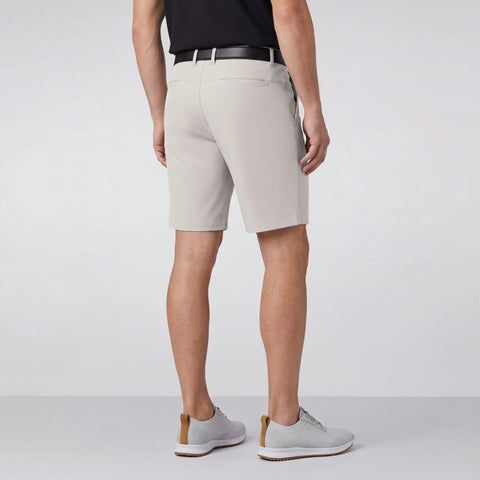 A man sitting wearing the Jetsetter Tech Short 9 inches in Sand Stone