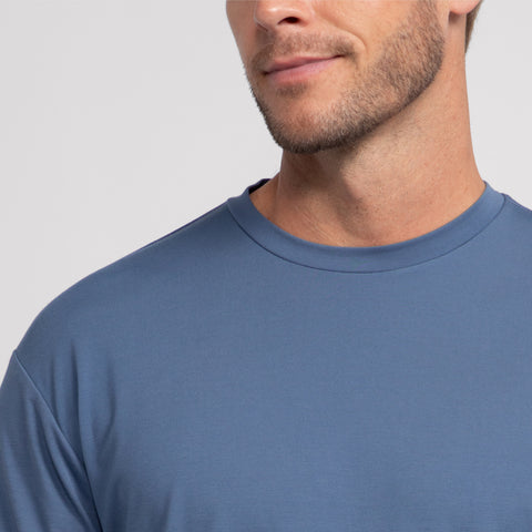A close-up of a man wearing the Jetsetter Tee in light blue, featuring only his chin, mouth, and part of his nose against a neutral light background.