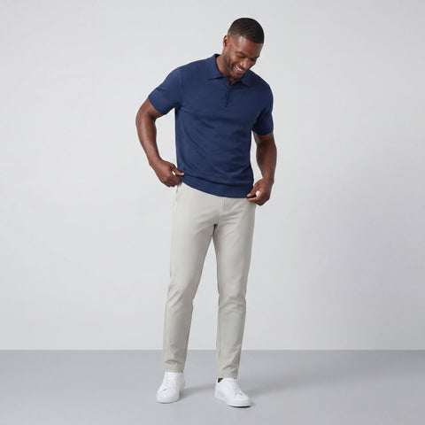 Man wearing a blue polo shirt and beige pants on a plain background