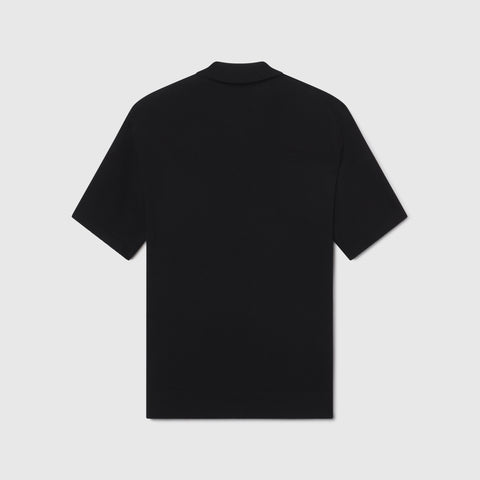 A man wearing the Legacy Resort Polo in True Black, lifestyle shot.