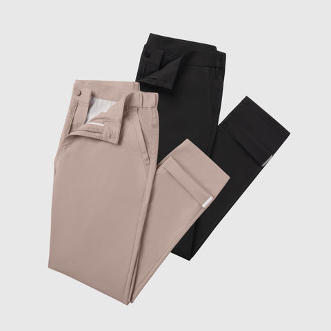 The Jetsetter Tech Pant Slim Fit 2-Pack features two folded pairs—one light beige and one black—each with visible front pockets and buttoned waistbands, displayed on a white background.