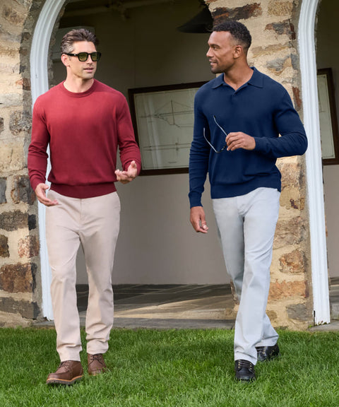 Two men walking outdoors in a red crewneck sweater and a navy knit polo.
