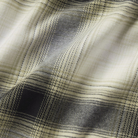 A man in the Anytime Plaid Shirt, Blackwatch Cream Plaid, seated