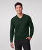 Pine green V-neck sweater worn with black trousers, hand in pocket.