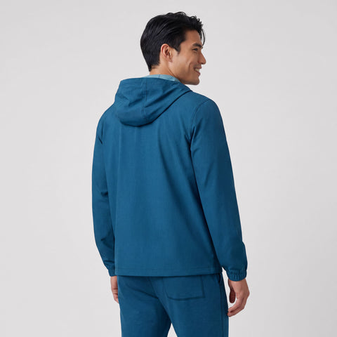 A man wearing the Clubhouse Range Hooded Jacket in Pacific Blue outdoors