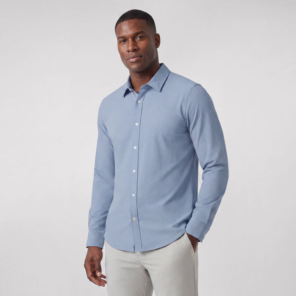 A man wearing the Everywear Shirt Shorter Length in Chambray Blue with a button-down collar.