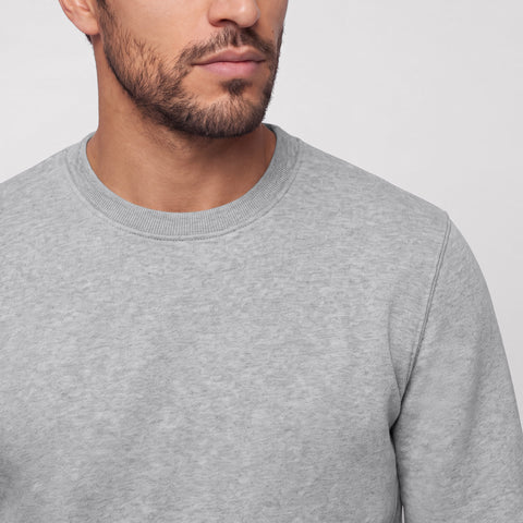 Close-up of a heather gray crewneck sweatshirt's ribbed collar and shoulder seam.
