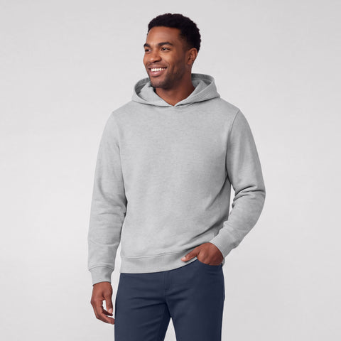 A man in a heather gray hooded sweatshirt and navy pants, smiling and looking to the side.