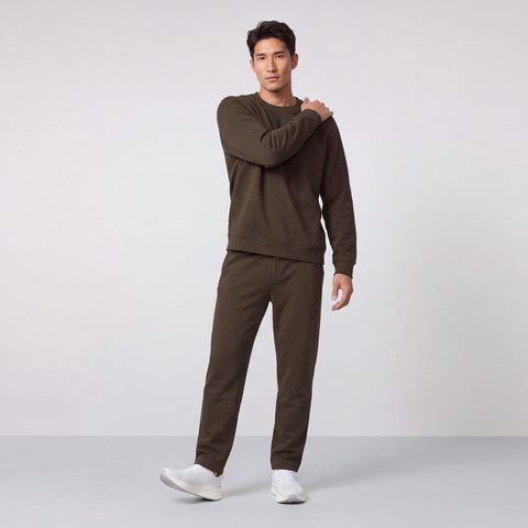 Man in an espresso brown crewneck sweatshirt and matching sweatpants, standing full length.