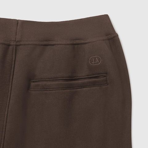 Close-up of the ribbed waistband and embroidered J.A back pocket on espresso brown sweatpants.