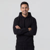 Man wearing a black hoodie with arms crossed on a light gray background