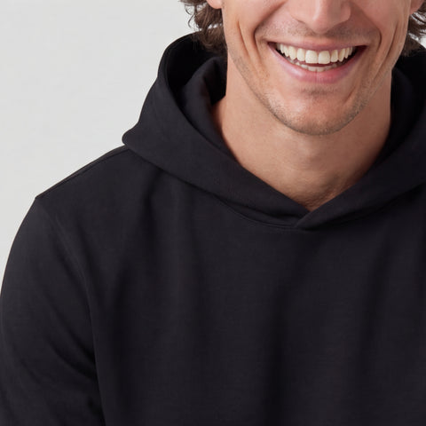 A man in the Sandwash Hoodie True Black in a casual lifestyle setting