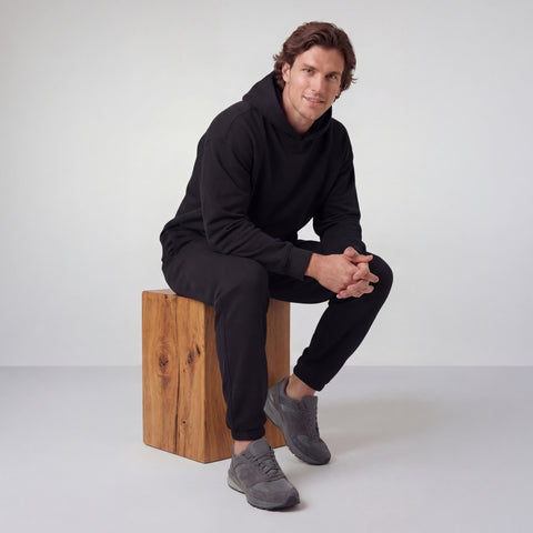 Man wearing the Sandwash Hoodie True Black in an outdoor environment
